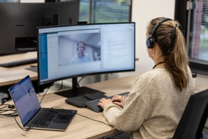 Vrouw achter computer in meeting met collega