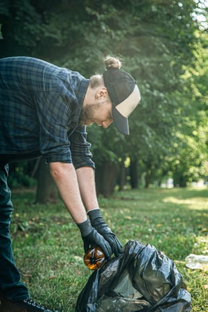 young-man-with-trash-bag-forest-cleans-up-plastic-bottles